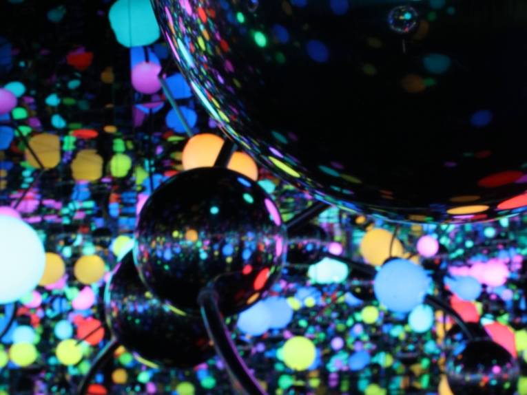 Zu sehen ist eine Nahaufnahme von bunten Lichtern vor schwarzem Grund.