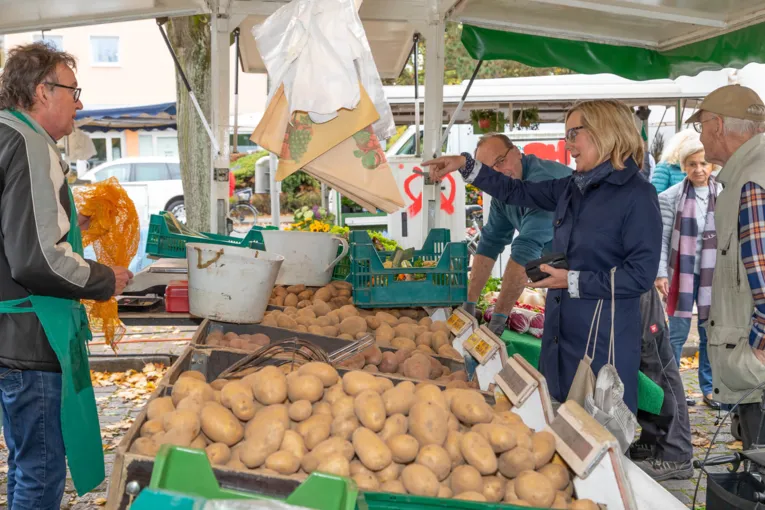 En kunde og en forhandler i samtale ved markedet ved kartoffelstanden.