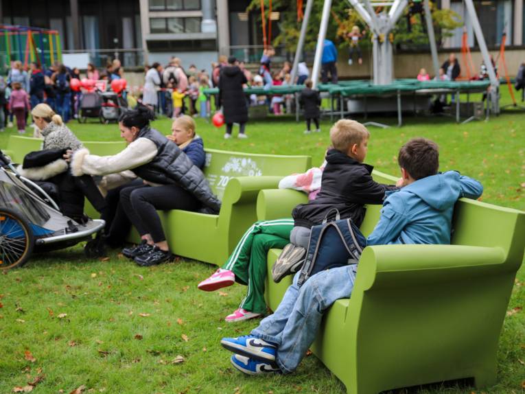 Kinder und Erwachsene auf grünen Sofas im Tiergarten.