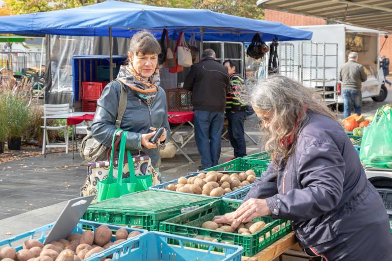 Eine Verk&auml;uferin packt f&uuml;r ihre Kundin Kartoffeln ab.