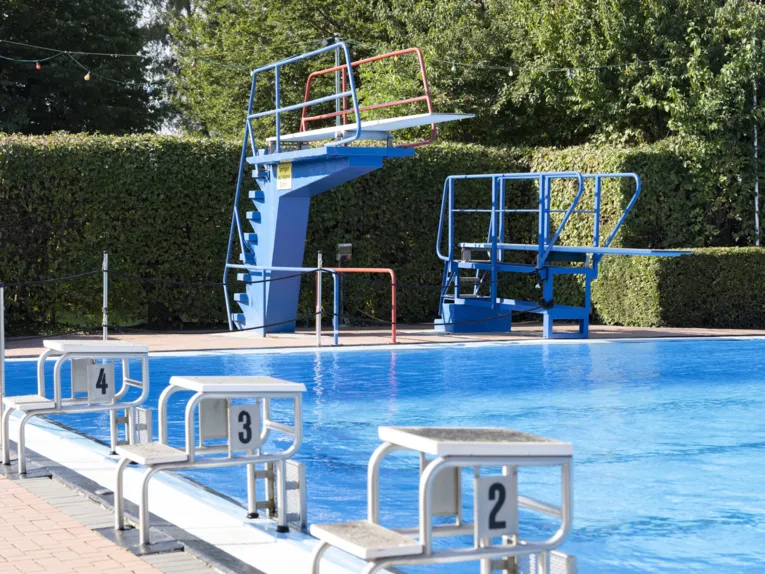 Zwei Sprungt&uuml;rme am Schwimmbeckenrand, davor Startbl&ouml;cke