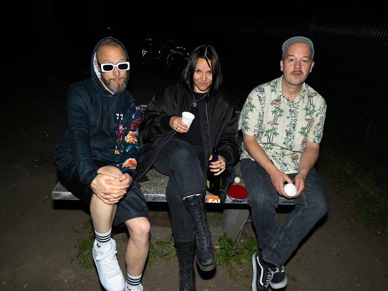 Die drei Bandmitglieder von „Großstadtgeflüster“ sitzen auf einer Tischtennisplatte