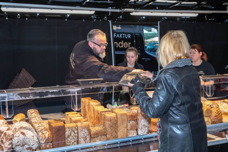 Eine Kundin kauft frische Backwaren bei einem Verk&auml;ufer in einem Marktwagen.