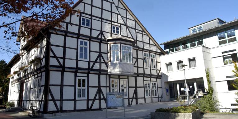 Fachwerkhaus mit weißen Fenstern und einem weißen Erker im ersten OG. Rechts am Fachwerkhaus befindet sich ein moderner Anbau in Kubusform.