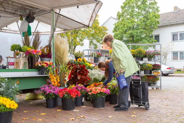 En bodholder på ugentlige markedet rådgiver en kunde om sit sortiment.