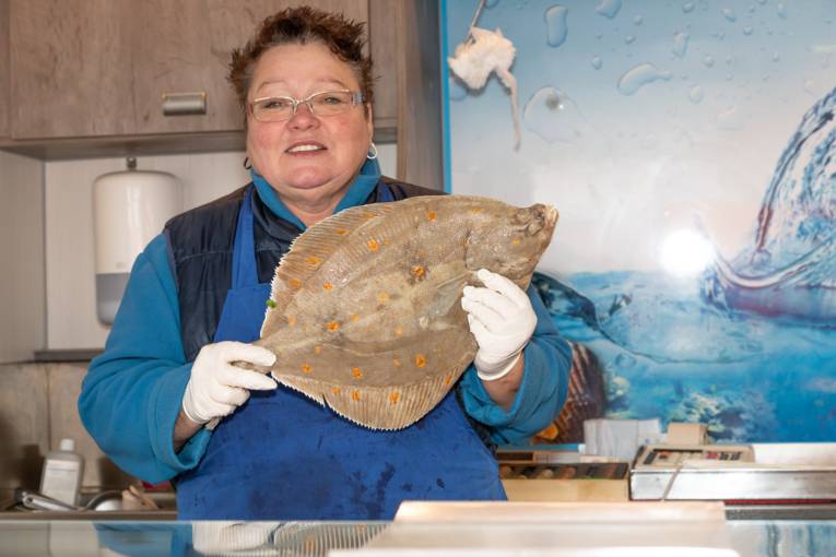 Eine Verk&auml;uferin h&auml;lt einen rohen, unverarbeiteten Fisch in die Kamera.