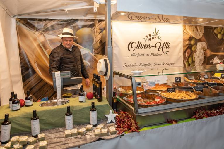 Ein Verk&auml;ufer an seinem Stand voll Mittelmeer-Spezialit&auml;ten.