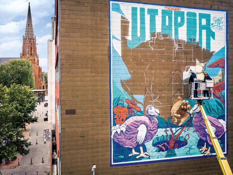 Zwei Kunstschaffenden besprühen eine Häuserwand in der Nordtstadt von Hannover