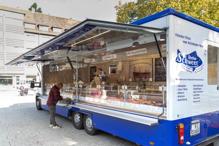 Kundin und Verkäufer an einem Fischstand auf dem Wochenmarkt