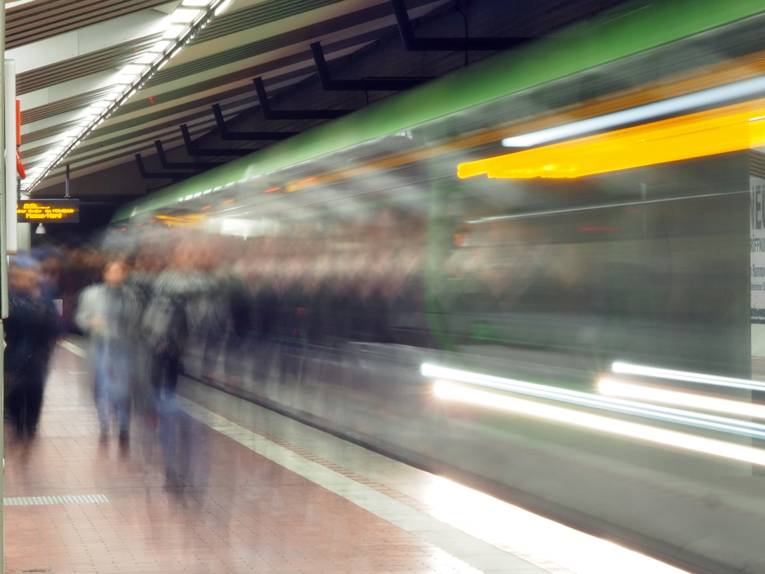 Unscharfes Bild einer Stadtbahn mit Fahrgästen an einer unterirdischen Haltestelle