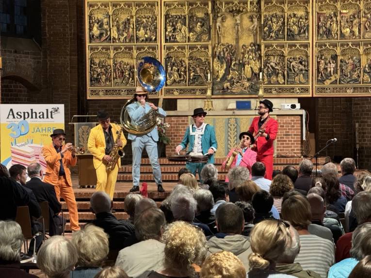 Band mit Blasinstrumenten in bunten Anzügen spielt auf der Altarbühne in der Marktkirche.