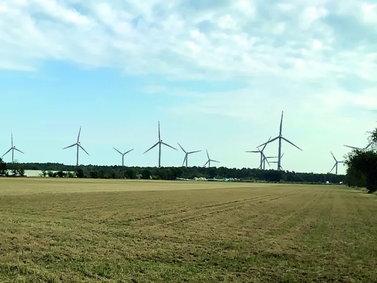 Windräder in einer Wald- und Wiesenlandschaft