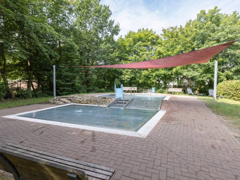 Zwei flache Becken , die über eine Metallrutsche verbunden sind und von einem Sonnensegel beschattet werden