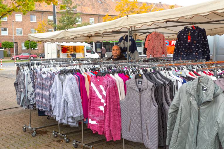 Ein Verk&auml;ufer inmitten seines Bekleidungsstandes.