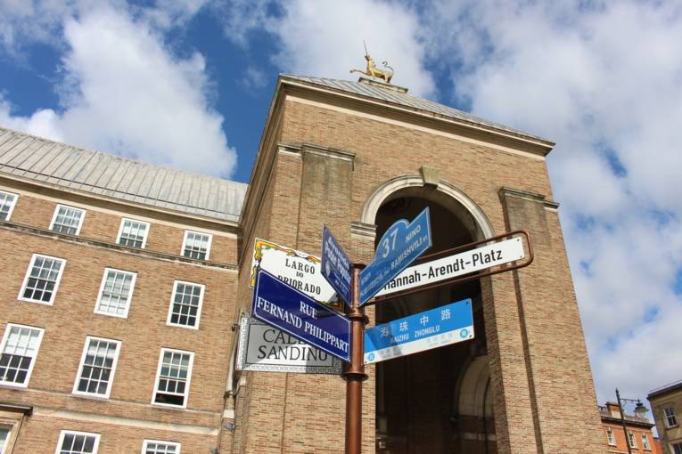 Sieben Straßenschilder zeigen in die Richtungen der Partnerstädte Bristols