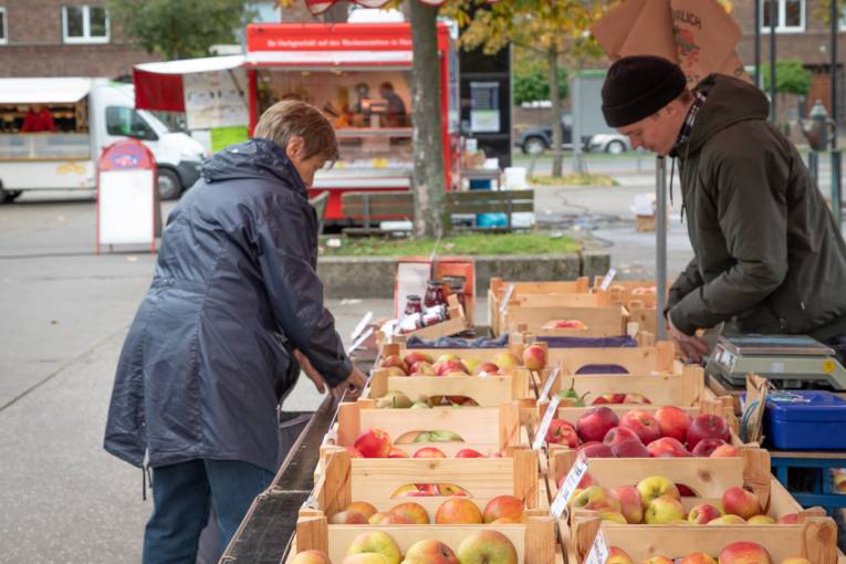 Eine Kundin und ein Verk&auml;ufer an einem Stand, an dem frische &Auml;pfel verkauft werden.