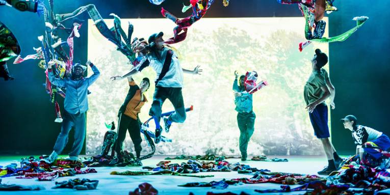 Fünf Personen in auf einer Bühnen werfen Fußball-Fan-Schals in die Höhe