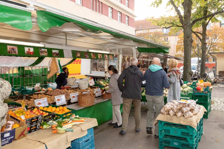 Menschen kaufen Obst und Gem&uuml;se an einem Marktwagen.