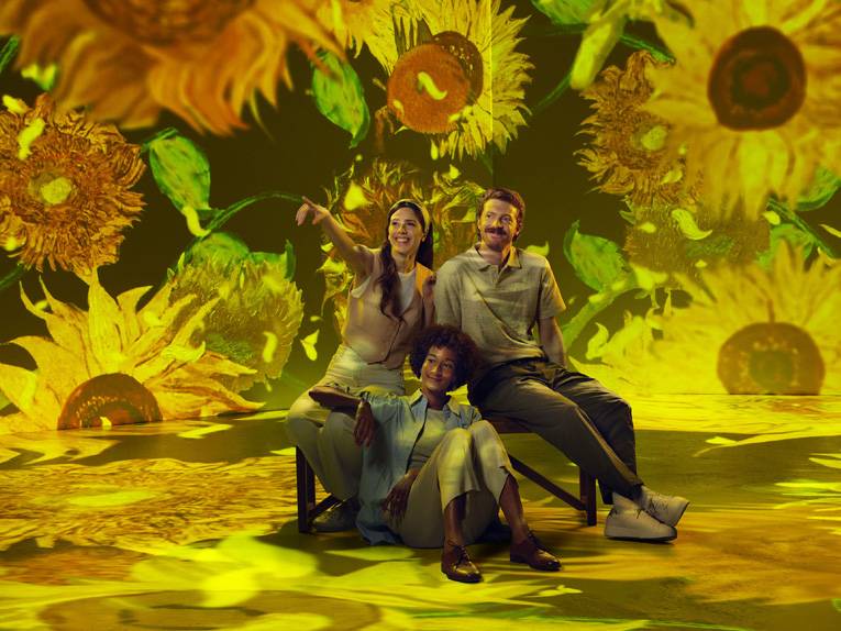 Eine Familie sitzt in einem Raum mit Wänden voller Sonnenblumen