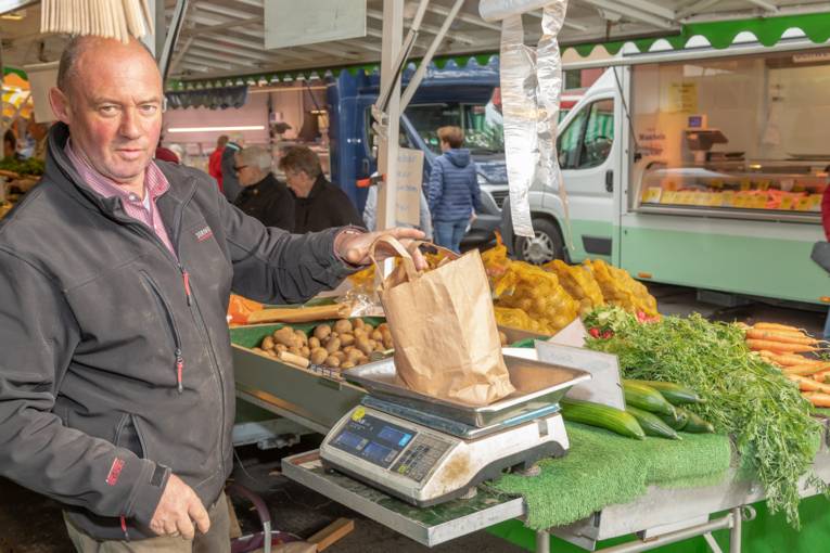 Ein Mann wiegt eine T&uuml;te mit Waren ab.