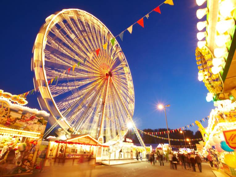 Une grande roue illuminée lors de la Fête du printemps, de nuit, à Hannover.