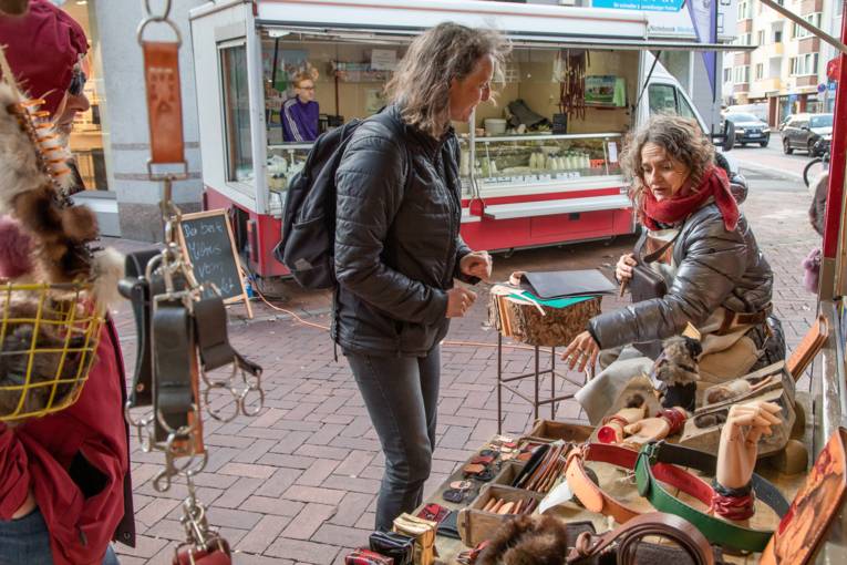 Eine Verk&auml;uferin und eine Kundin an einem Stand f&uuml;r Lederwaren.