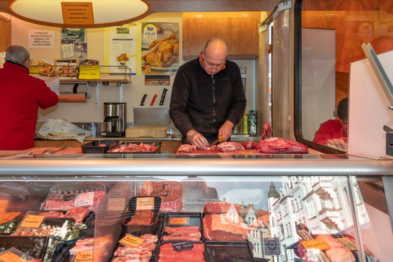 Ein Verkäufer schneidet Wurstwaren.