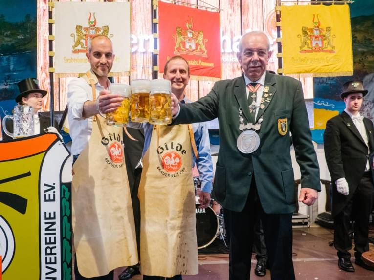 Drei Männer mit Bierkrügen.