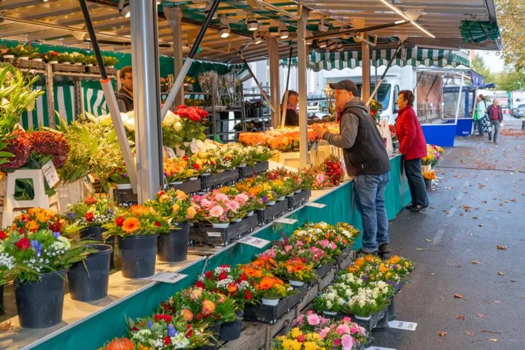 Folk ved en blomstervogn på ugentlige marked.