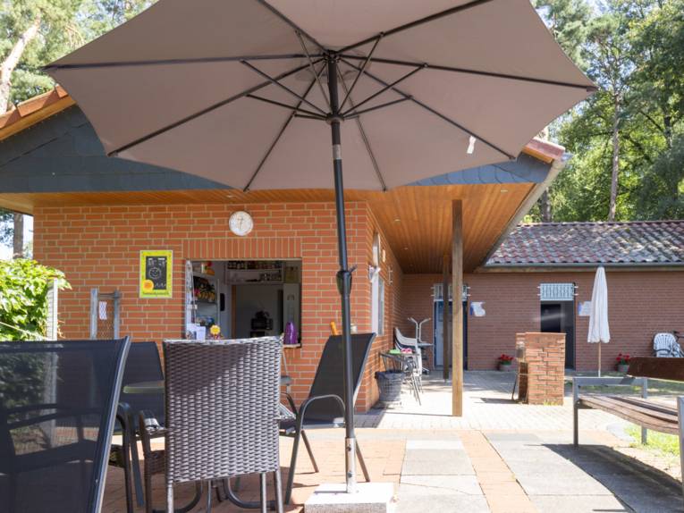 Geb&auml;ude, eine Terasse mit Sonnenschirmen, Tischen und St&uuml;hlen