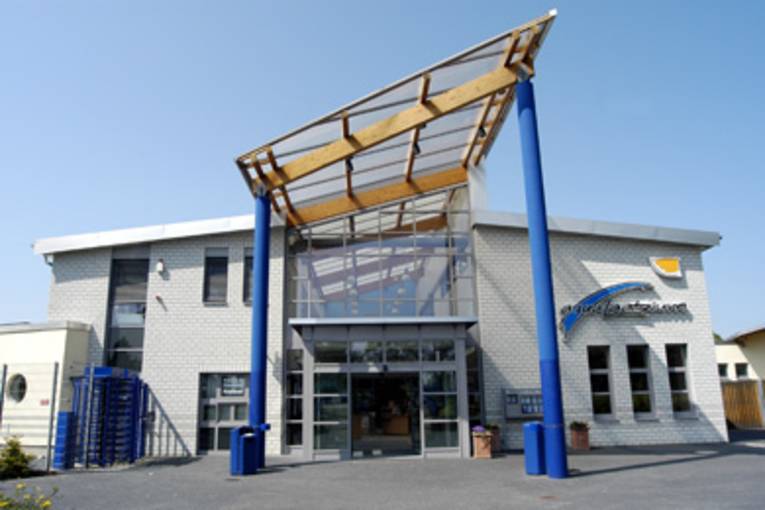 Gebäudeeingang mit einem Glasdach auf blauen Stahlsäulen