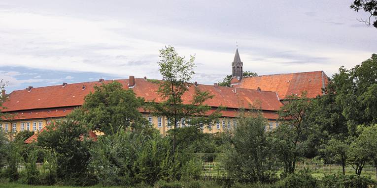 Großes Gebäude mit rotem Dach hinter hohen Sträuchern