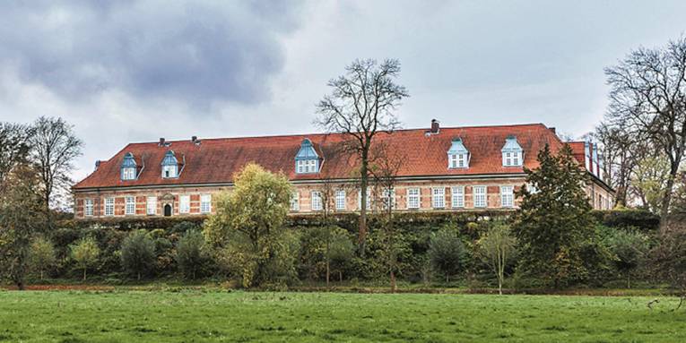 Wiese und auf einem Hügel ein altes Gebäude