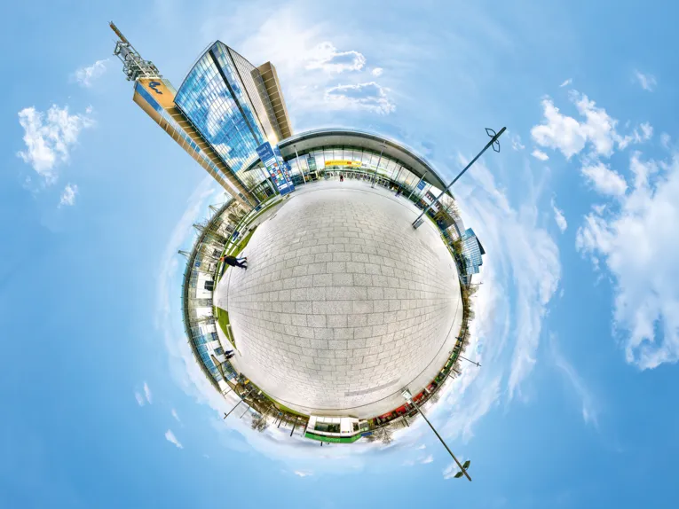 Creative 360-degree view of the Hanover Exhibition and Congress Center in "Little Planet" style with high-rise building and entrance area.