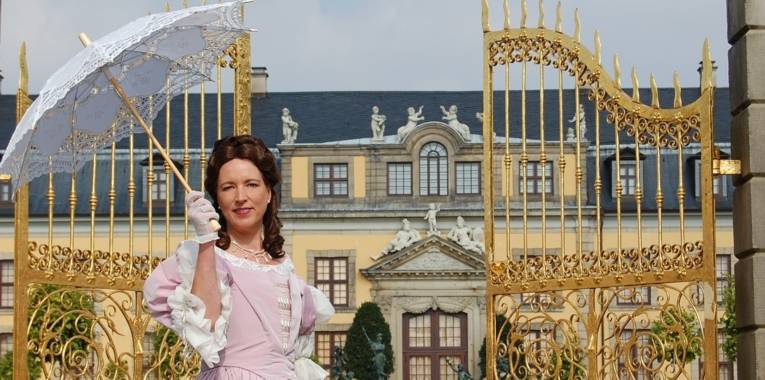 Eine Frau steht im Kostüm von Kurfürstin Sophie vor dem Goldenen Tor.