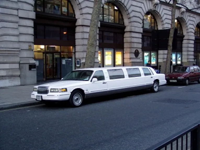 A Liomousine is parked in front of a building. 