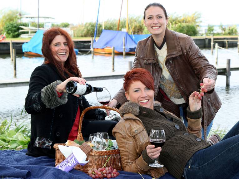 Drei Frauen sitzen auf einer Decke.