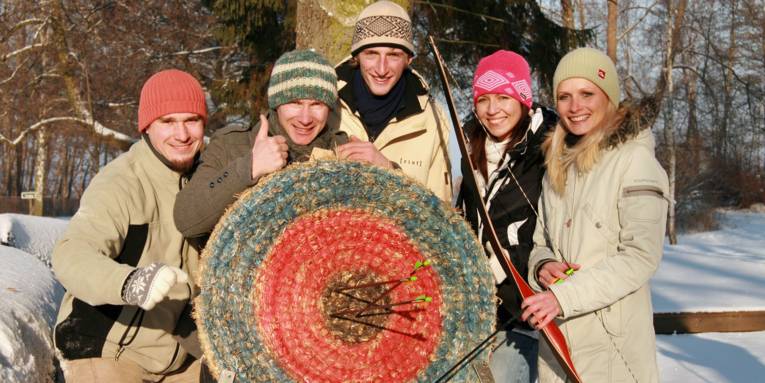 junge Menschen im Schnee mit Zielscheibe für Bogenschießen