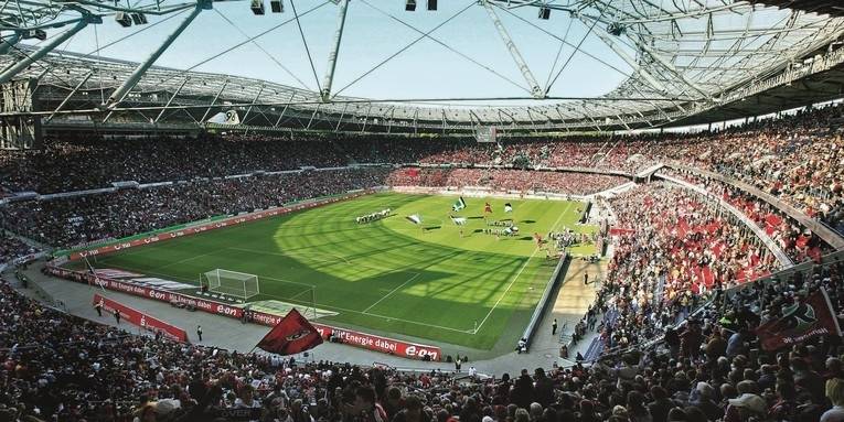 Das Bild zeigt eine Innenansicht des Hannover 96 Stadions, in dem ein Spiel ausgetragen wird.