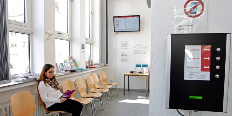 I venteområdet på borgerkontoret i Herrenhausen sidder en ung kvinde og læser en brochure, mens det elektroniske skilt viser oplysninger om de ledige betjeningspladser.