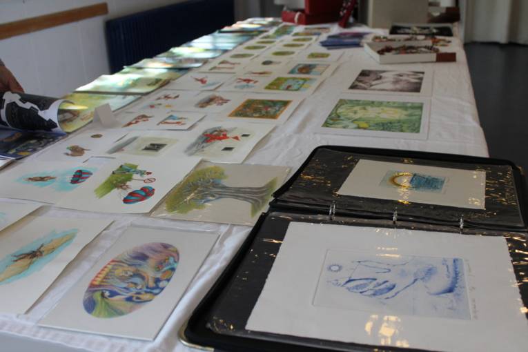 Auf dem Bild ist ein Tisch zu sehen, auf dem verschiedene Malereien liegen.