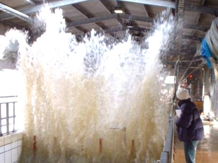 ca. 3 Meter hohe Welle im Wellenkanal, an der rechten Seite eine Besucherin 