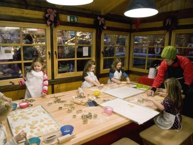 Children cut out cookie dough with baking tins