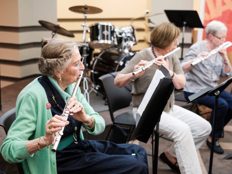 Drei Damen mit Querflöte spielen im Sitzen auf einer Bühne - das Ensemble Andantino der Musikschule