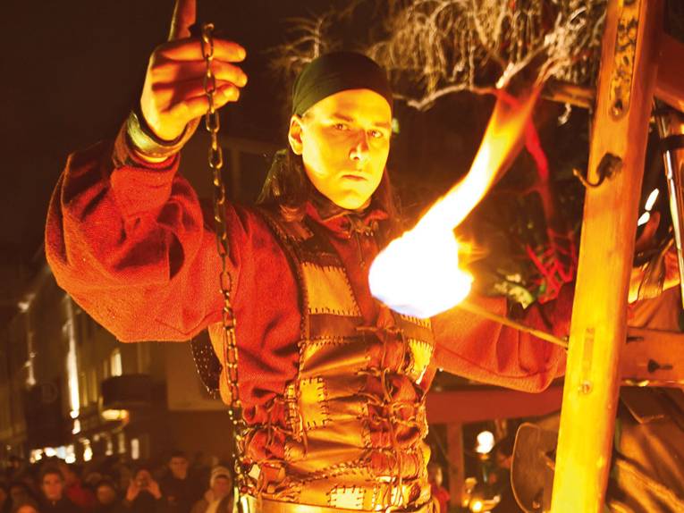 Ein Feuerkünstler in historischer Kleidung bei seiner Darbietung im historischen Dorf auf dem Weihnachtsmarkt Hannover
