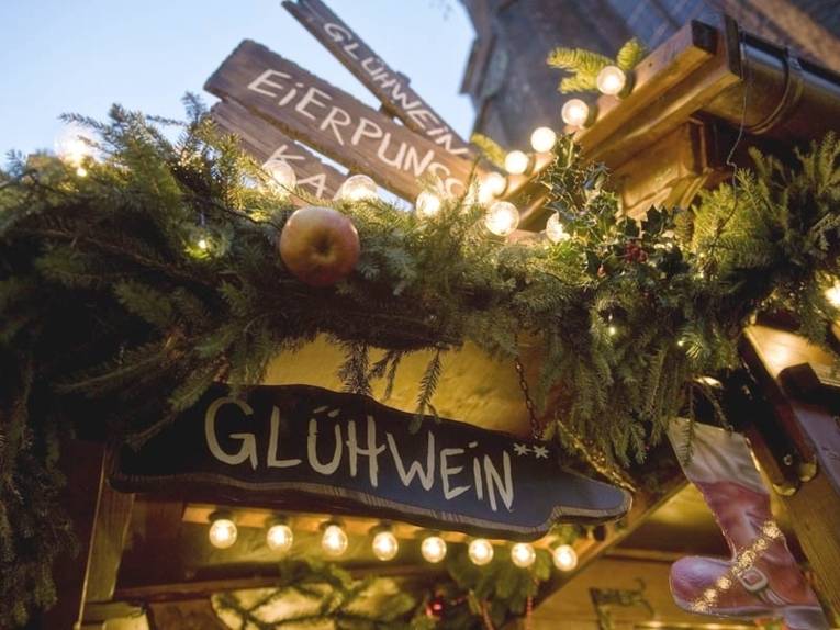 Holzschilder mit der Aufschrift "Glühwein", "Eierpunsch" und "Kakao" auf dem Weihnachtsmarkt