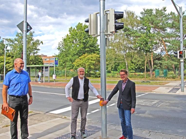 Drei Männer an einer Ampel. 