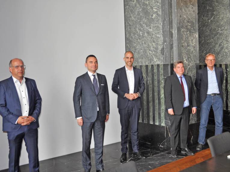 Fünf Männer in einem Saal. 