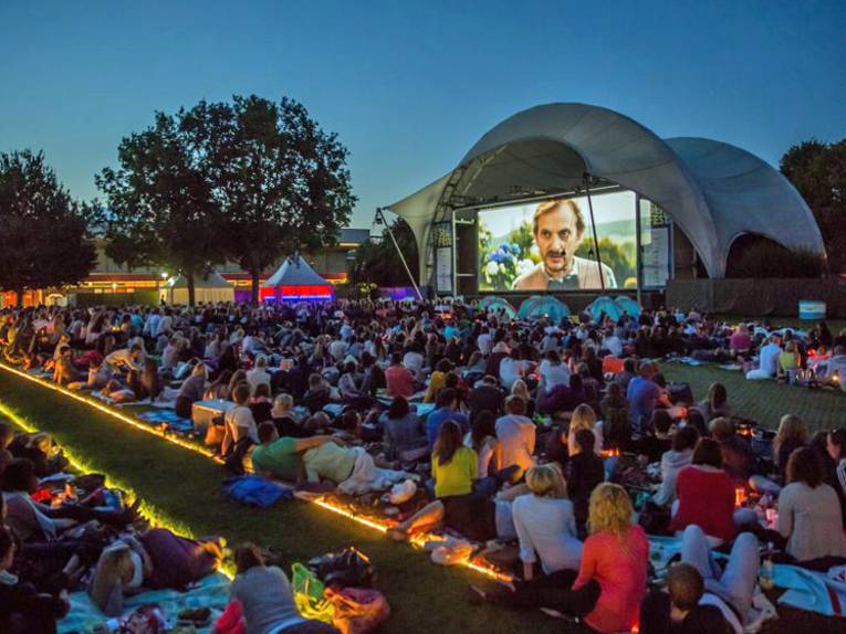 Leute im Freien vor einer großen Leinwand