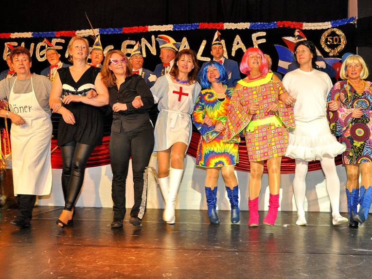 Verschieden verkleidete Frauen tanzen in einer Reihe auf einer Bühne.